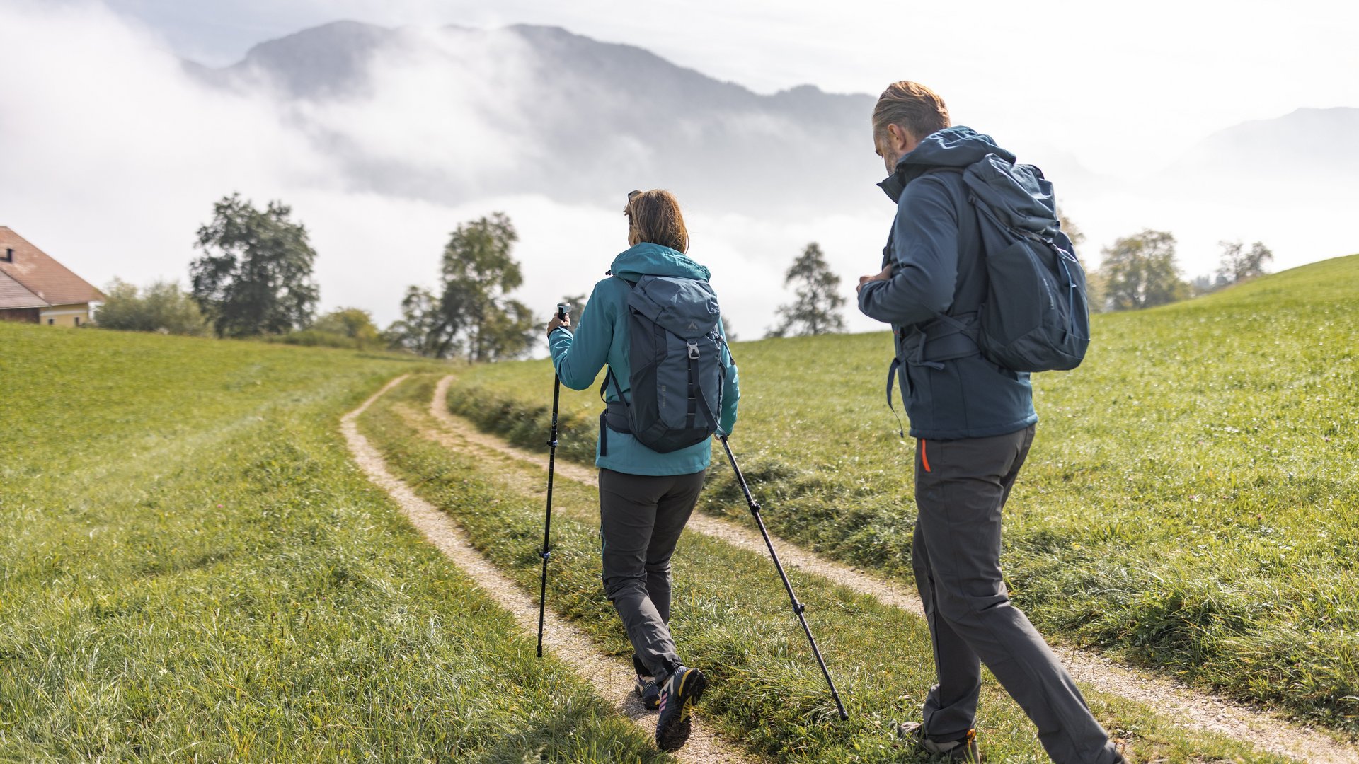 Eine Frau und ein Mann wandern einen Feldweg in der Attersee-Region.